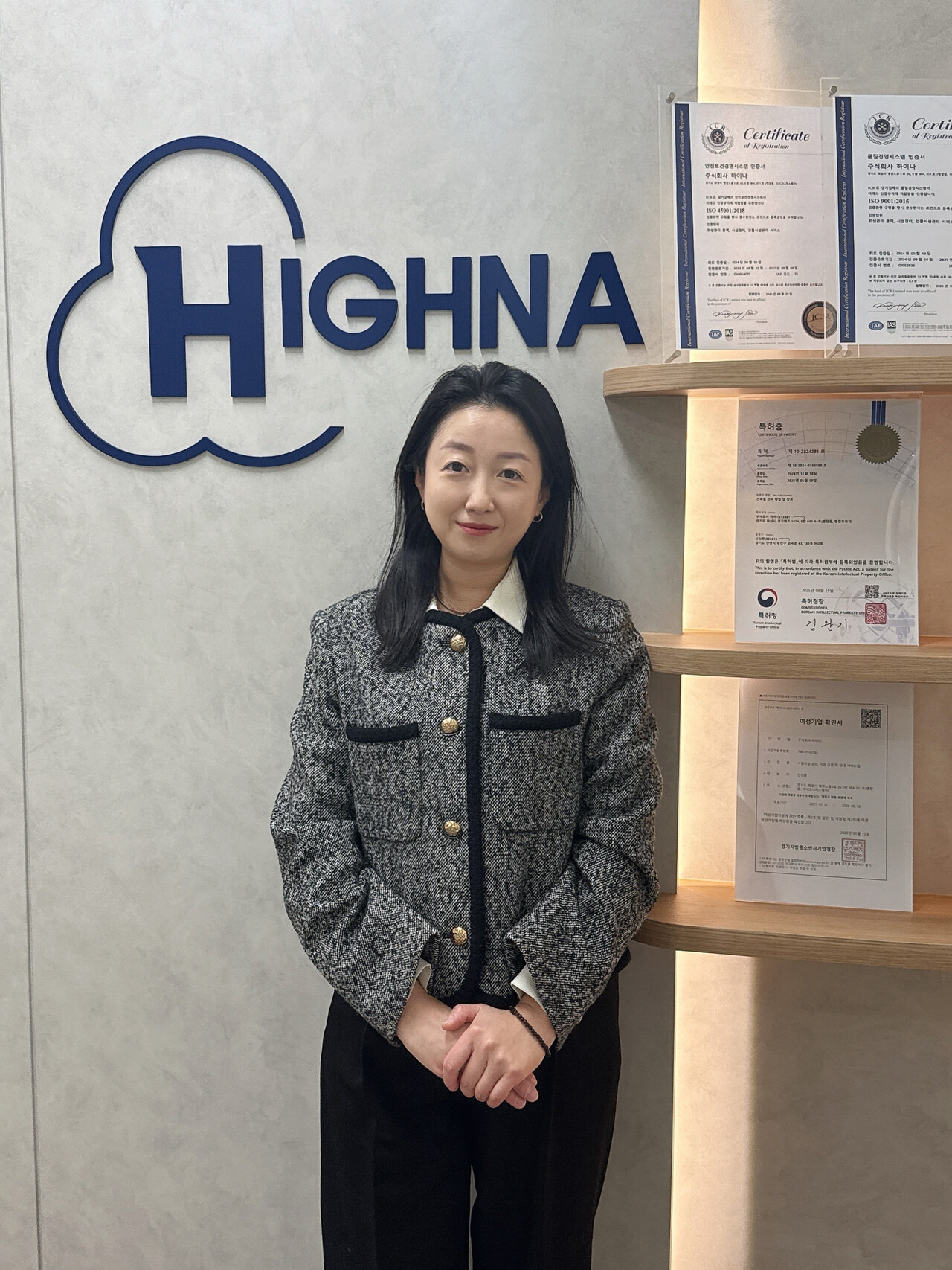 ㈜하이나 신선화 대표가 본사 로비에서 회사 로고와 인증서 앞에 포즈를 취하고 있다.하이나는 ISO 인증 등 다수의 공인 자격을 보유하며, 2022년 창립 이후 건물종합관리·시설위탁·인력아웃소싱 분야에서 빠른 성장을 이어가고 있다.